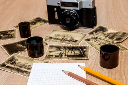 Old camera on the table with notebook, pen, negative film strip