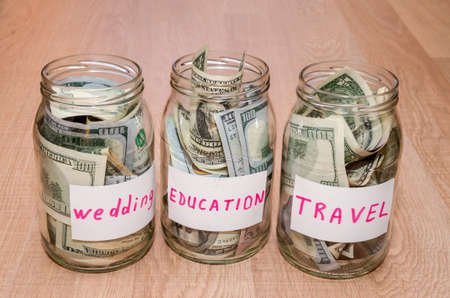 Dollar in glass jar with house, car, education, wedding, travel label, financial conceptの写真素材