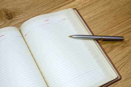 top view of old open book with fountain pen on wooden tableの写真素材