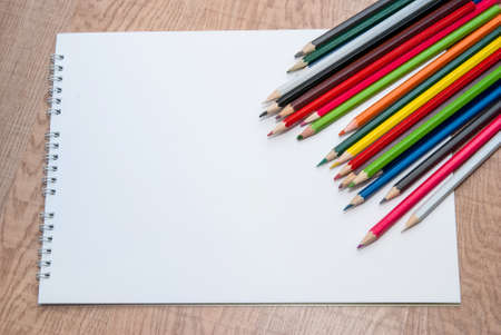 empty white paper and colorful pencils on the wooden tableの写真素材