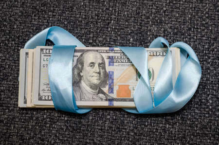 one hundred dollar bills in blue gift ribbonの写真素材