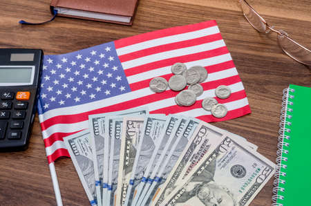 usa flag with dollar bills and coins, calculator, notepad on tableの写真素材