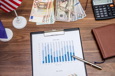 Dollar, Euro currency and flag with coin, notepad on tableの写真素材