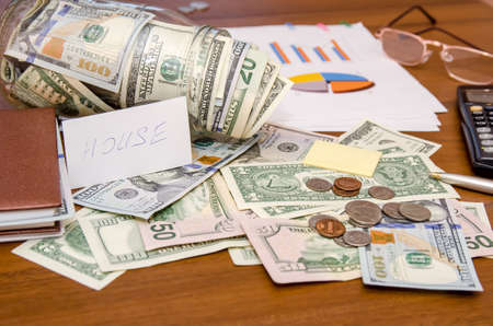 dollar bills in jar with chart and calculator on tableの写真素材
