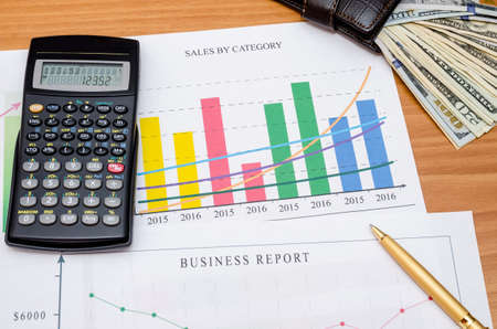 Graphs, charts, business table with money, calculator and pen on tableの写真素材