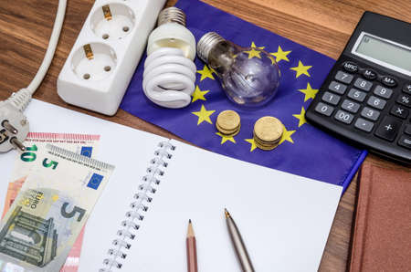 Light Bulbs on european banknotes with empty notepad and pen, calculator. Savings conceptの写真素材