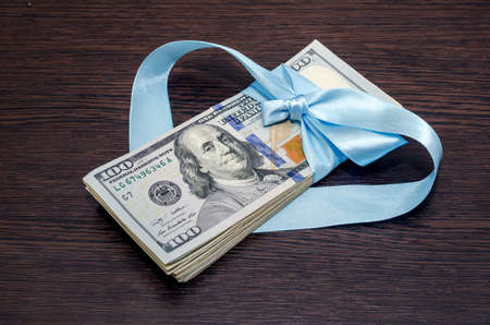 one hundred dollar bills in blue gift ribbonの写真素材