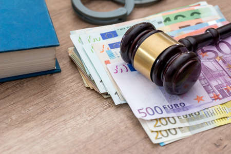 euros bills, handcuff and hammer on desk.