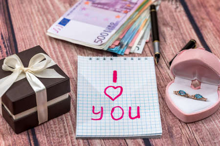 text i love you with gold earrings, money on desk.の写真素材