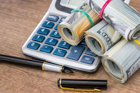 rolls dollar with calculator and pen on desk.の写真素材