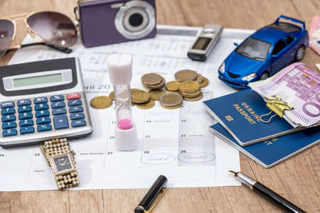 time to travel - passport, money, camera, watch, calculator, glasses, calendar toy car on wooden table.の写真素材