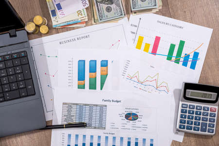 Financial charts, graphs, diagrams, financial report, computer and pen on wooden desk.