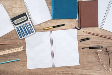 Student desk, calculator, pen, blank writing book, glasses