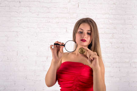 lovely girl with magnifying glass and bitcoin in studio