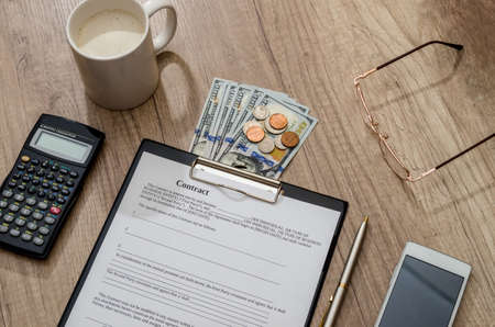 coffee and contract, money, mobile phone on deskの写真素材