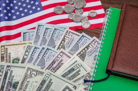 us dollar banknote with coins and flag, notepad, pen on table