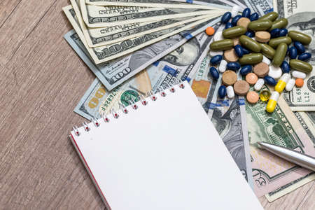 dollar, pills and pen on table