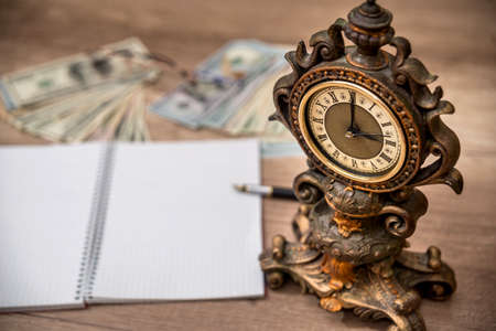 old clock with empty notepad. money and penの写真素材