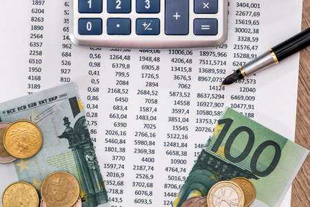 Budget text with 100 euros torn, calculator, pen with coinsの写真素材