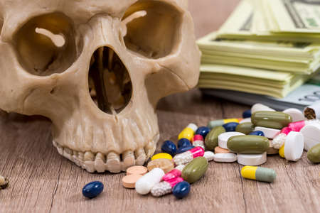 plastic skull of dollars, pills, drugs and syringes.の写真素材