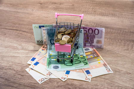 Euro money in a shopping cart on a wooden tableの写真素材