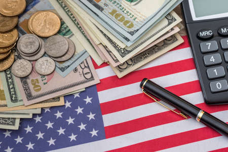 business concept - us flag, dollar banknotes, us cent coin, pen and calculator.の写真素材