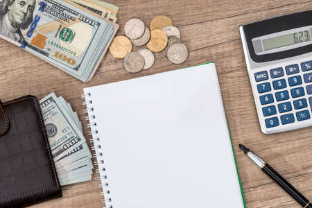 notepad with pen, calculator, dollar bills on desk.の写真素材