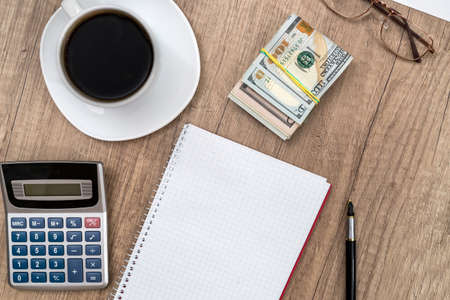 empty notepad with pen, calculator, coffee and dollar