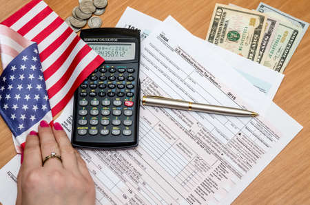 Tax form with money, pen and calculator, flag
