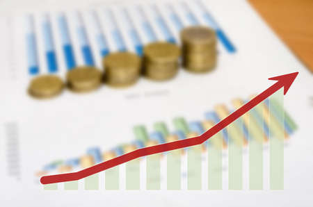 Graph and money coins with arrow on the table