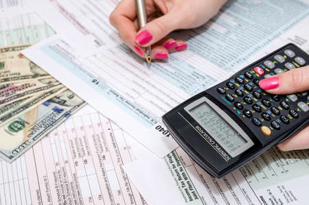 business woman holding pen and calculator on Tax Form 1040の写真素材
