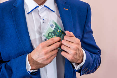 Businessman putting 100 euro bills in his pocket.