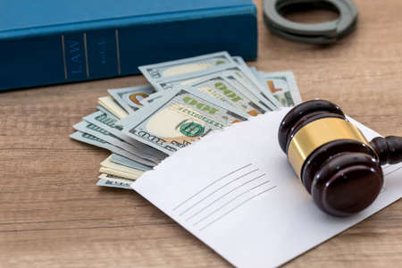 corruption. dollars in an envelope, handcuffs, gavel and book judge.