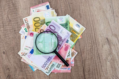 different euros banknotes under magnifying glass on desk.の写真素材