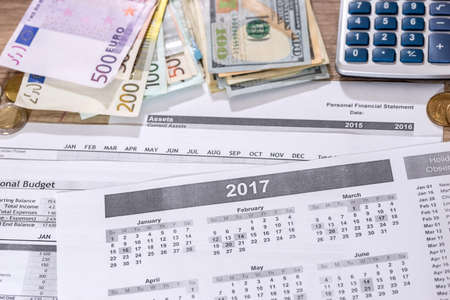 euro and dollar bills, calculator, ink pen and coin money on calendar background