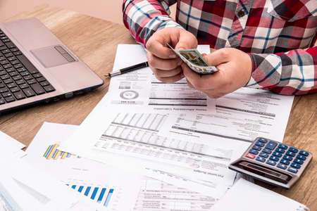 man counts money for office work and computer calculation of the budget