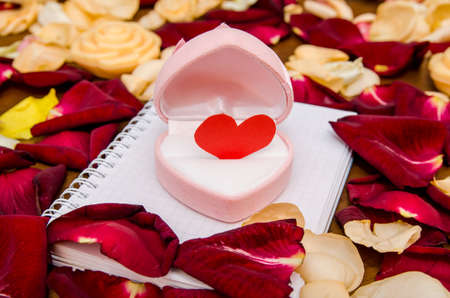 valentines day - empty notepad and gift box with many rose petals. Top viewの写真素材