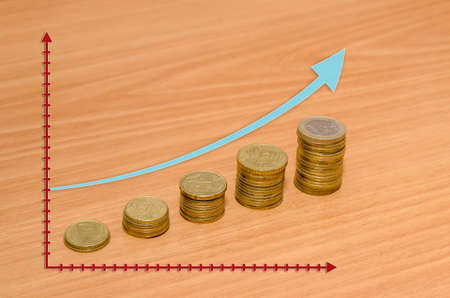Golden euro coins with a arrow on wooden background