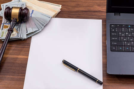 Labor law concept, laptop, gavel, money, pen and note on wooden tableの写真素材