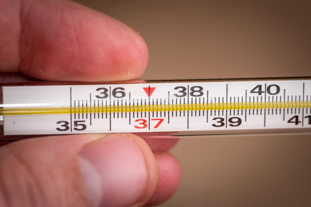 thermometer in hand on the background of pillsの写真素材