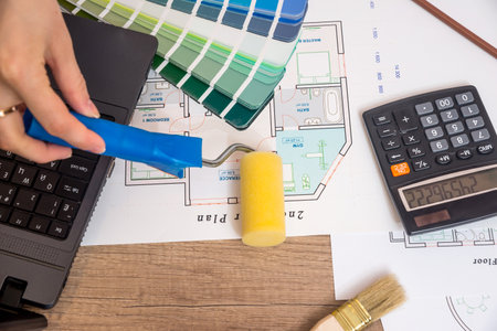 Architect sketching a construction project with laptop, color palette and work tools