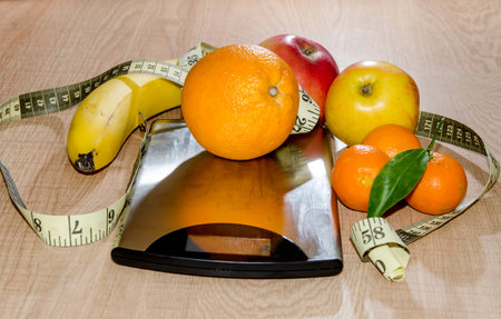 Concept of diet. Low-calorie fruit over measuring weight