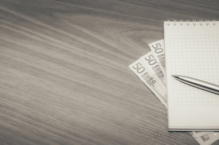 empty notepad with euro banknote, pen on tableの写真素材
