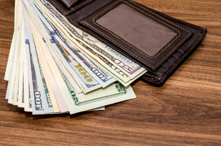 Wallet with us dollar bills on wooden table