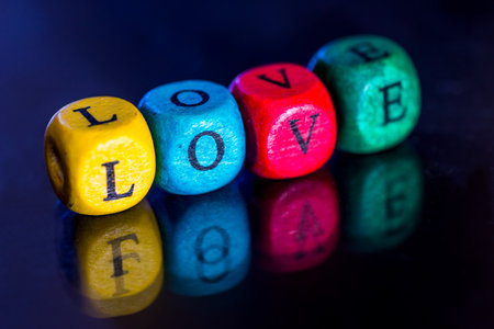 Word "love" of the colored wooden cubes isolated on dark background.の写真素材