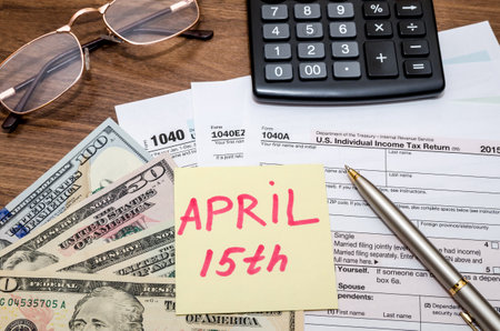 1040 tax form with sticky note of april 15, us dollar and calculatorの写真素材