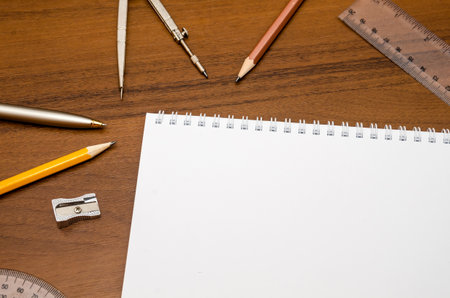 Office workplace - empty notepad, pen, pencil, ruler, compass on dark wooden background