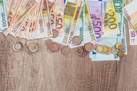 many euro coin and banknotes on wooden deskの写真素材