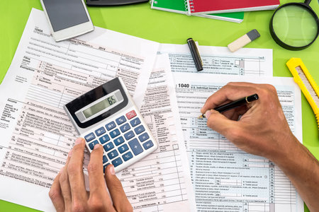 man filling tax form with pen, calculatorの写真素材