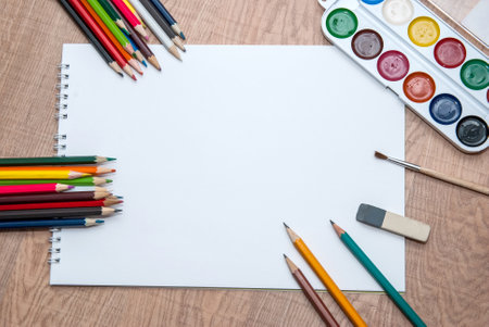 set of colorful paints, crayons and brushes with blank albumの写真素材